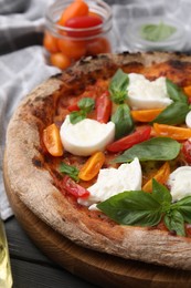 Delicious pizza with burrata cheese, tomatoes and basil on table, closeup