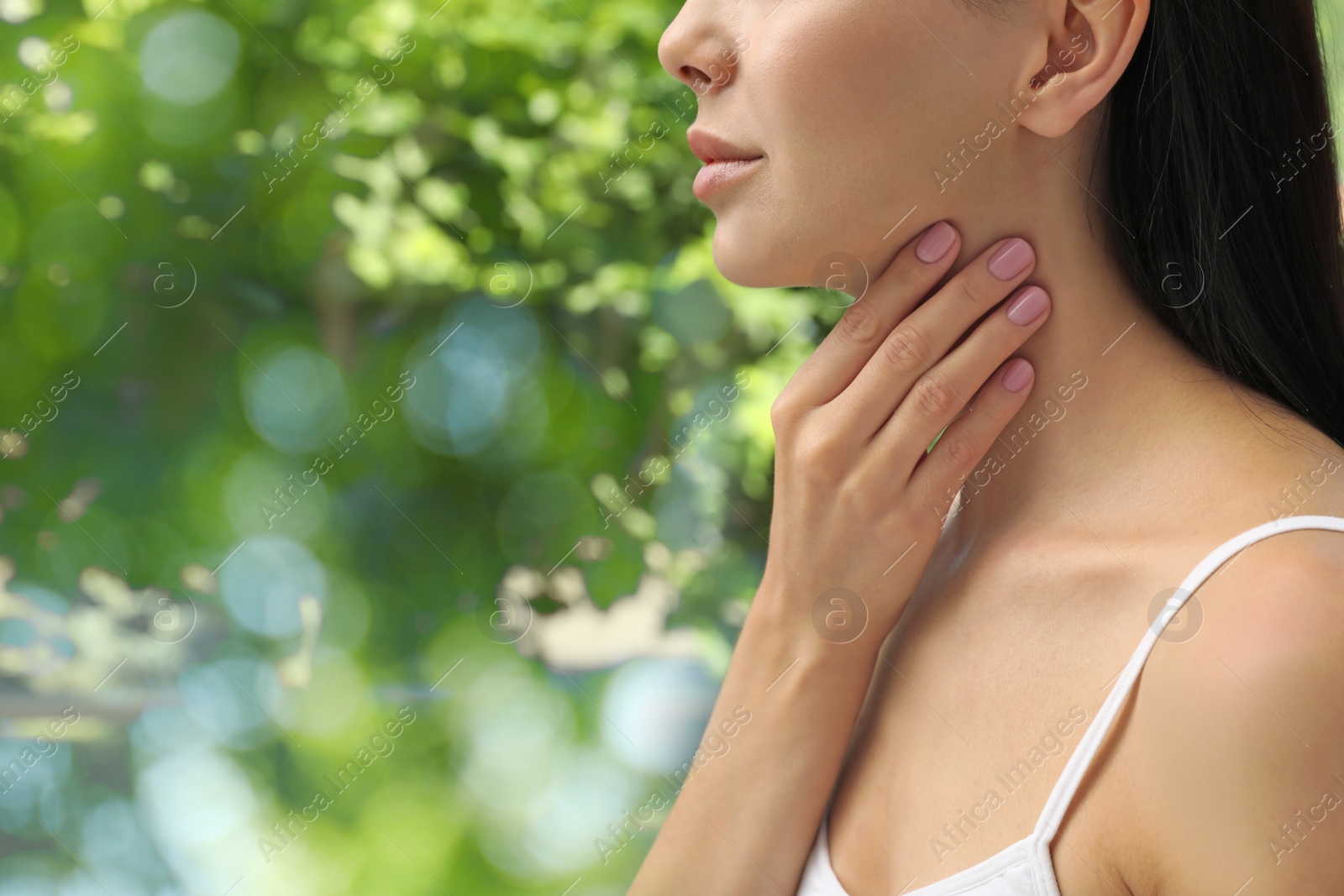 Photo of Young woman doing thyroid self examination near window, closeup. Space for text