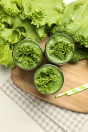 Photo of Green smoothie of lettuce leaves in glasses on white wooden table, flat lay
