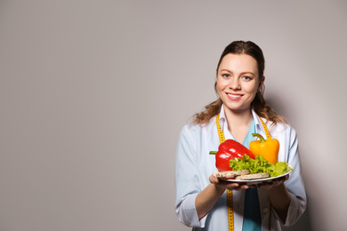 Photo of Nutritionist with healthy products on light grey background. Space for text
