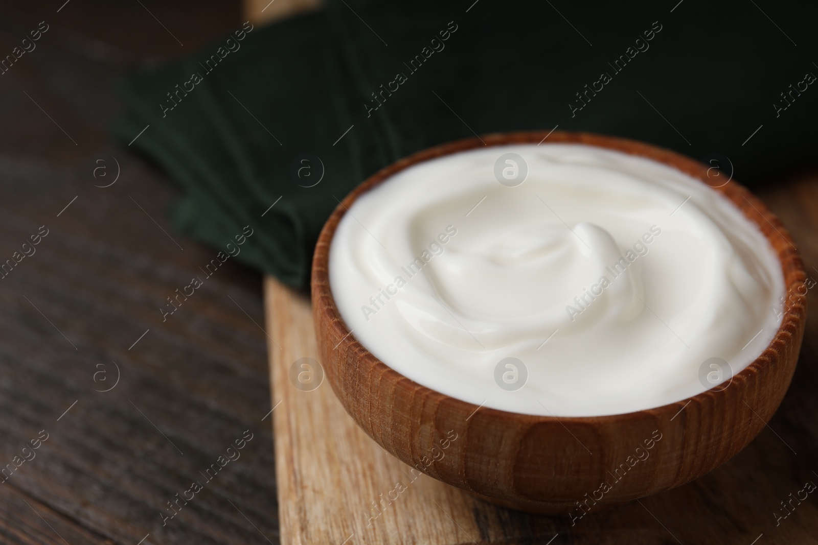 Photo of Delicious natural yogurt in bowl on wooden table, closeup. Space for text