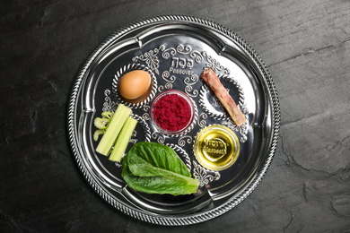 Photo of Passover Seder plate (keara) on black table, top view. Pesah celebration