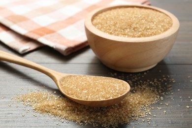 Photo of Brown sugar in bowl and spoon on wooden table, closeup