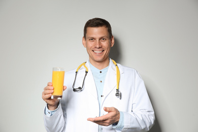 Nutritionist with glass of juice on light grey background
