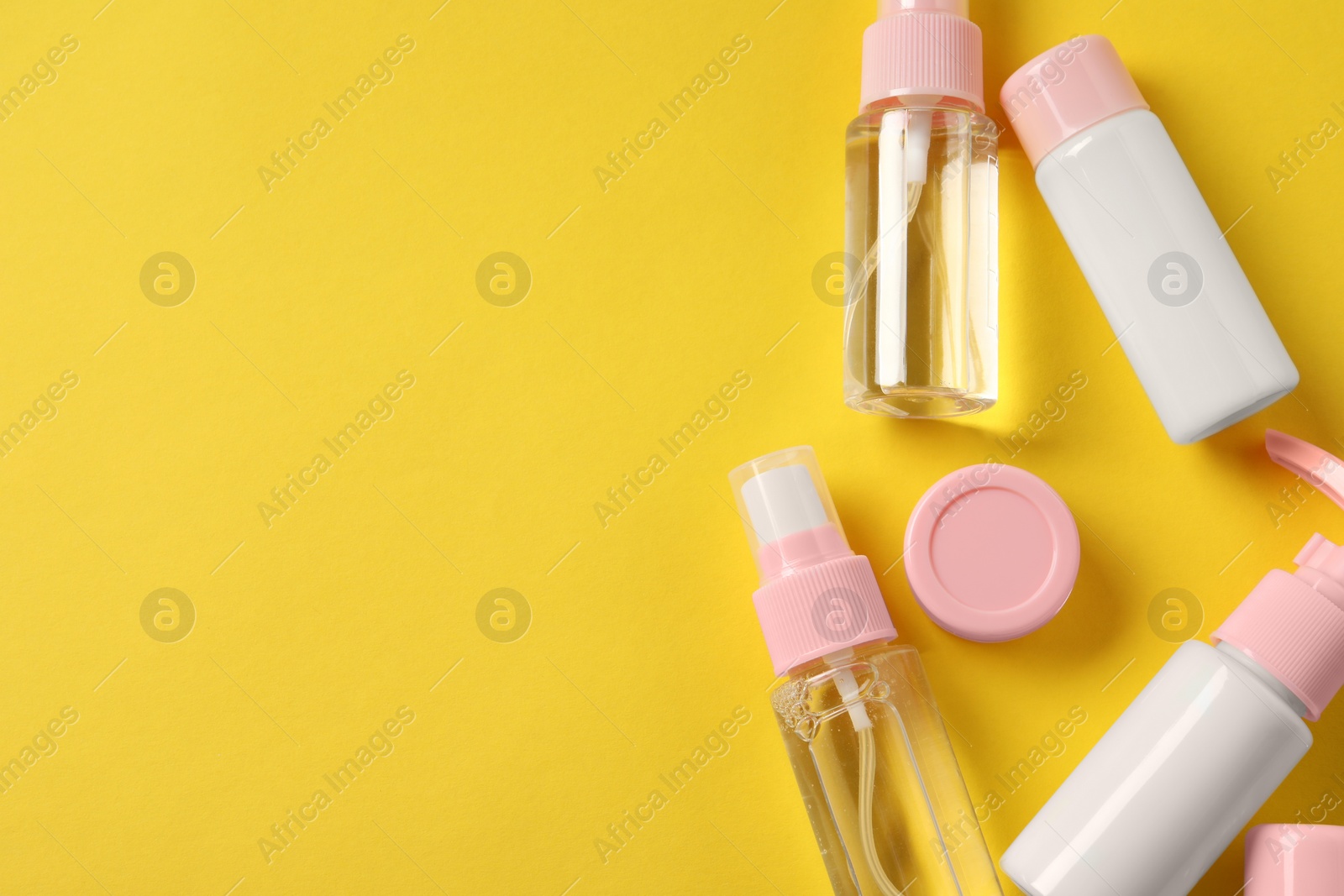 Photo of Cosmetic travel kit on yellow background, flat lay. Space for text