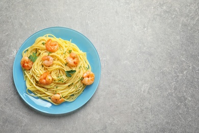 Plate with spaghetti and shrimps on grey background, top view