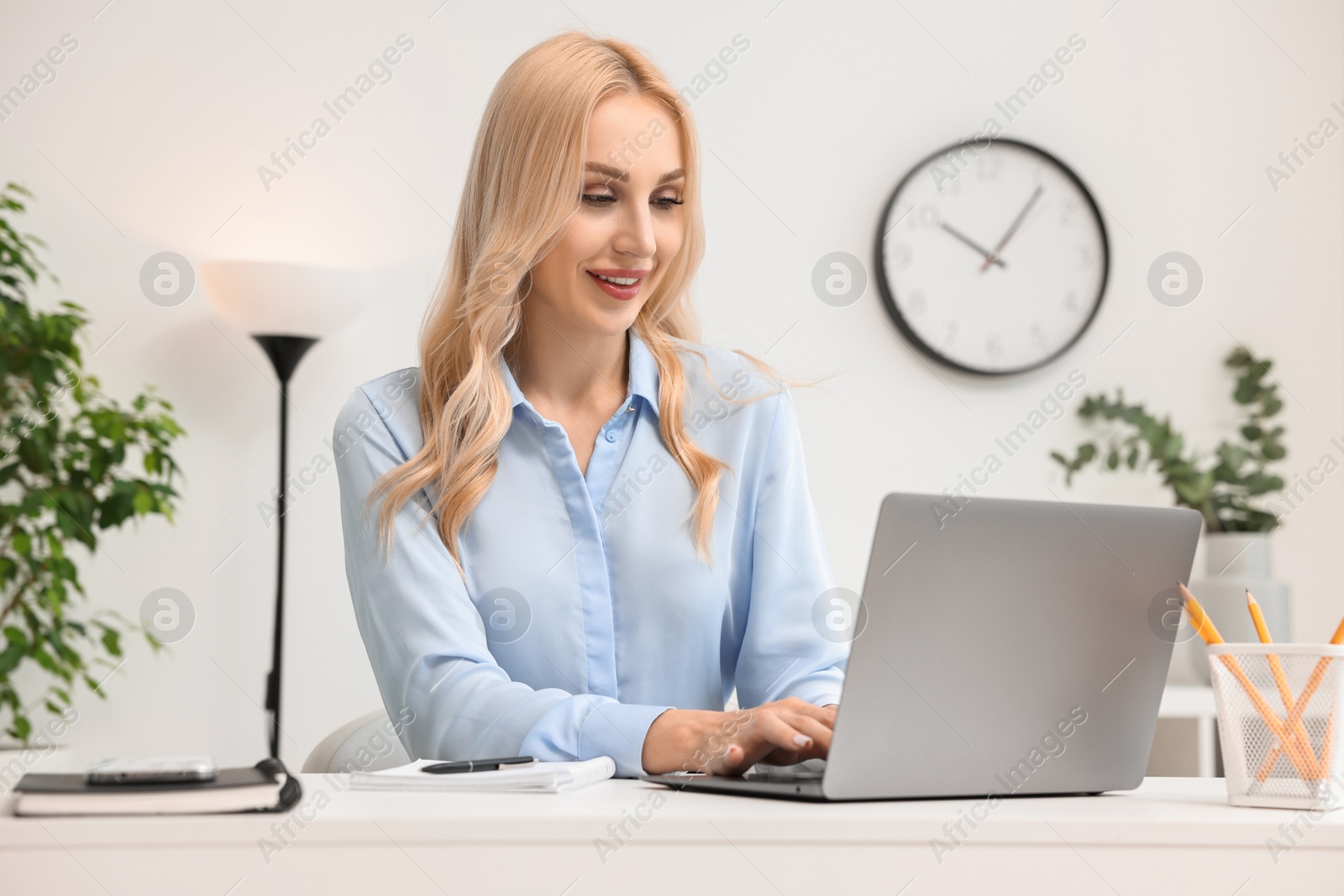 Photo of Happy secretary working with laptop in office