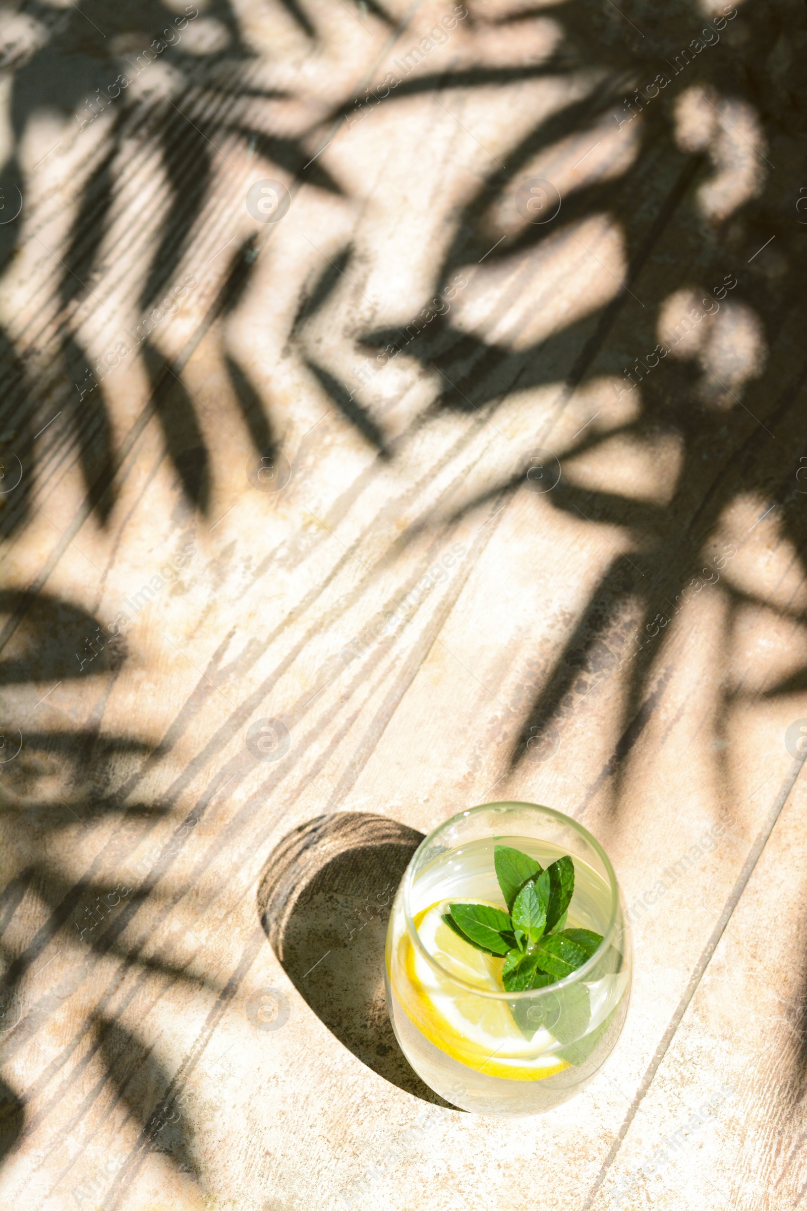 Photo of Refreshing water with lemon and mint on wooden table, space for text