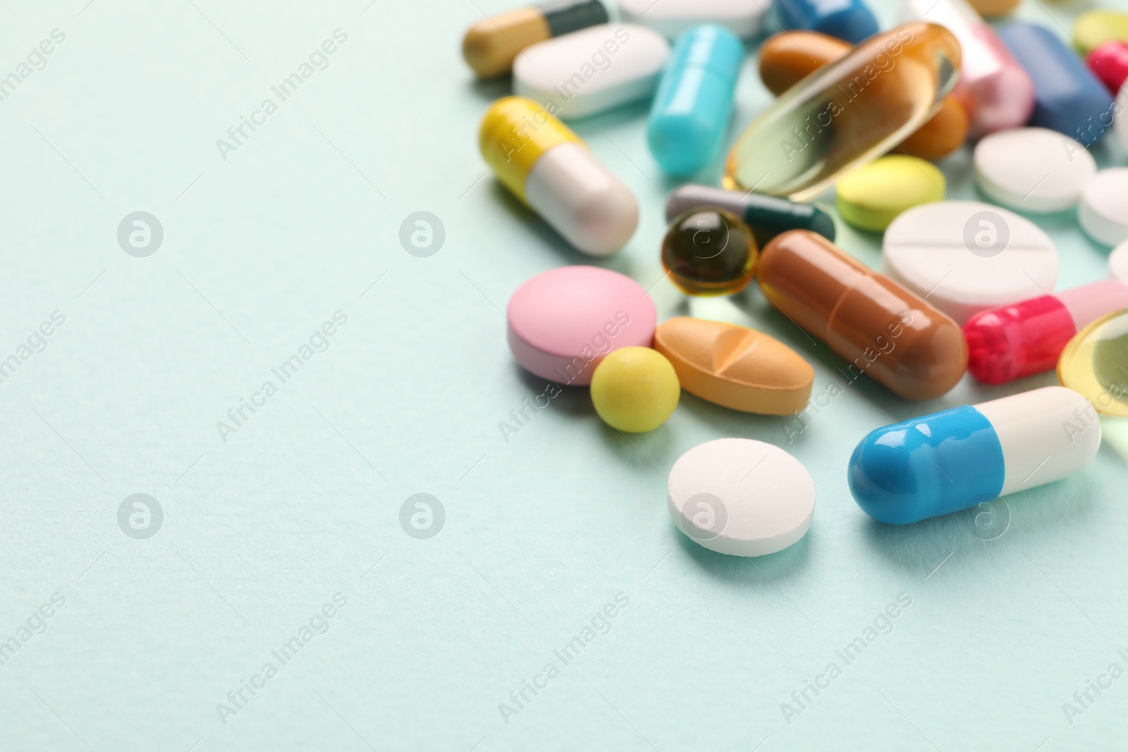 Photo of Pile of different pills on mint background, selective focus. Space for text