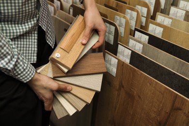 Photo of Man with samples of wooden flooring in shop, closeup