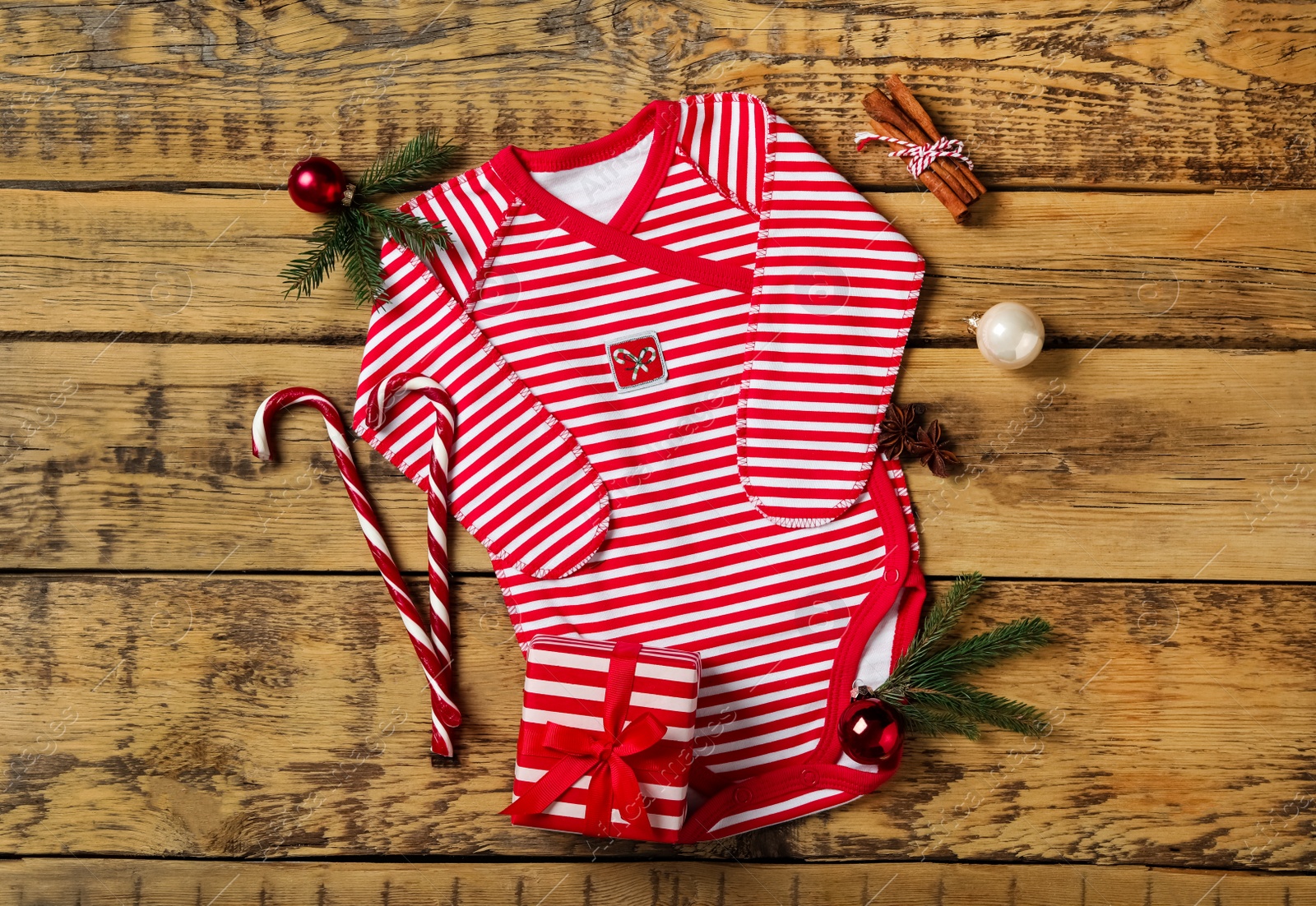 Photo of Striped baby bodysuit and Christmas decorations on wooden background, flat lay