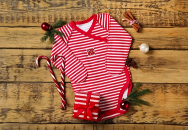 Photo of Striped baby bodysuit and Christmas decorations on wooden background, flat lay