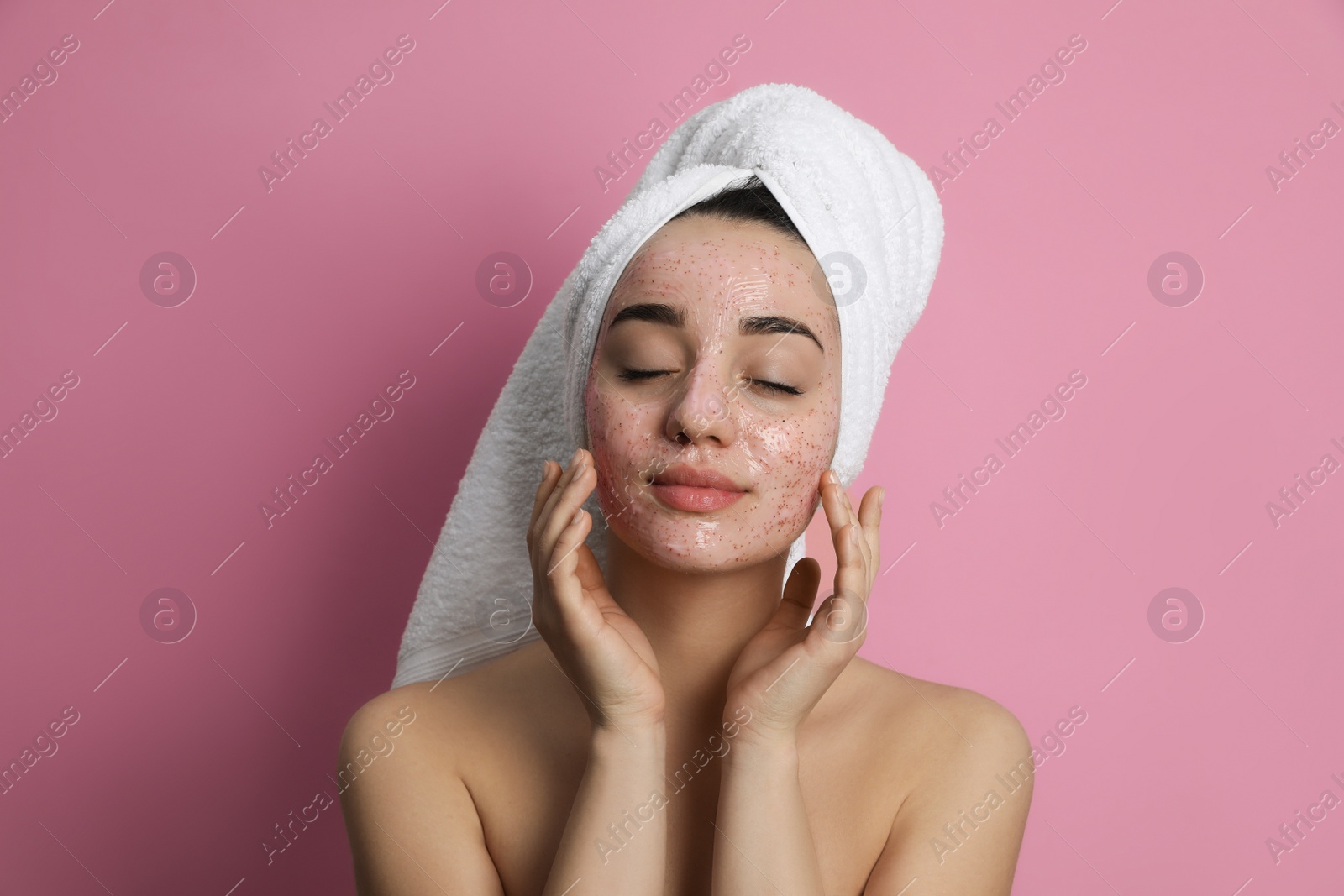 Photo of Woman applying pomegranate face mask on pink background