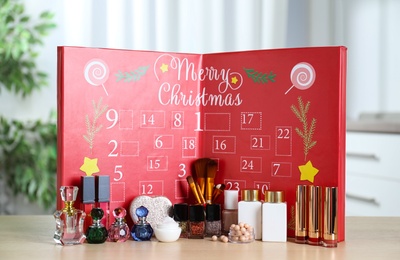 Photo of Advent calendar with different cosmetics and perfumes on wooden table. Presents for Christmas