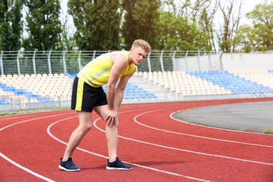 Man in sportswear suffering from knee pain at stadium