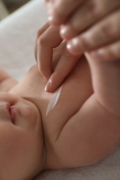 Photo of Mother applying body cream on her little baby, closeup