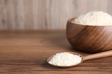 Photo of Uncooked rice on wooden table. Space for text