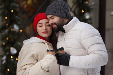 Lovely couple with hot drinks spending time together outdoors