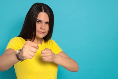 Photo of Young woman ready to fight on light blue background, space for text