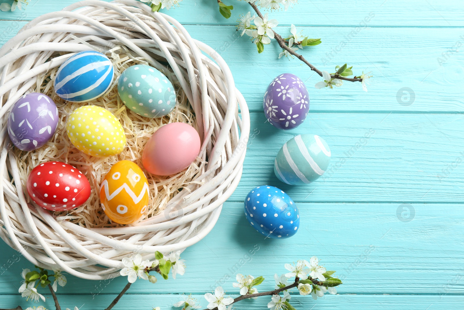 Photo of Flat lay composition with painted Easter eggs and blossoming branches on wooden background. Space for text