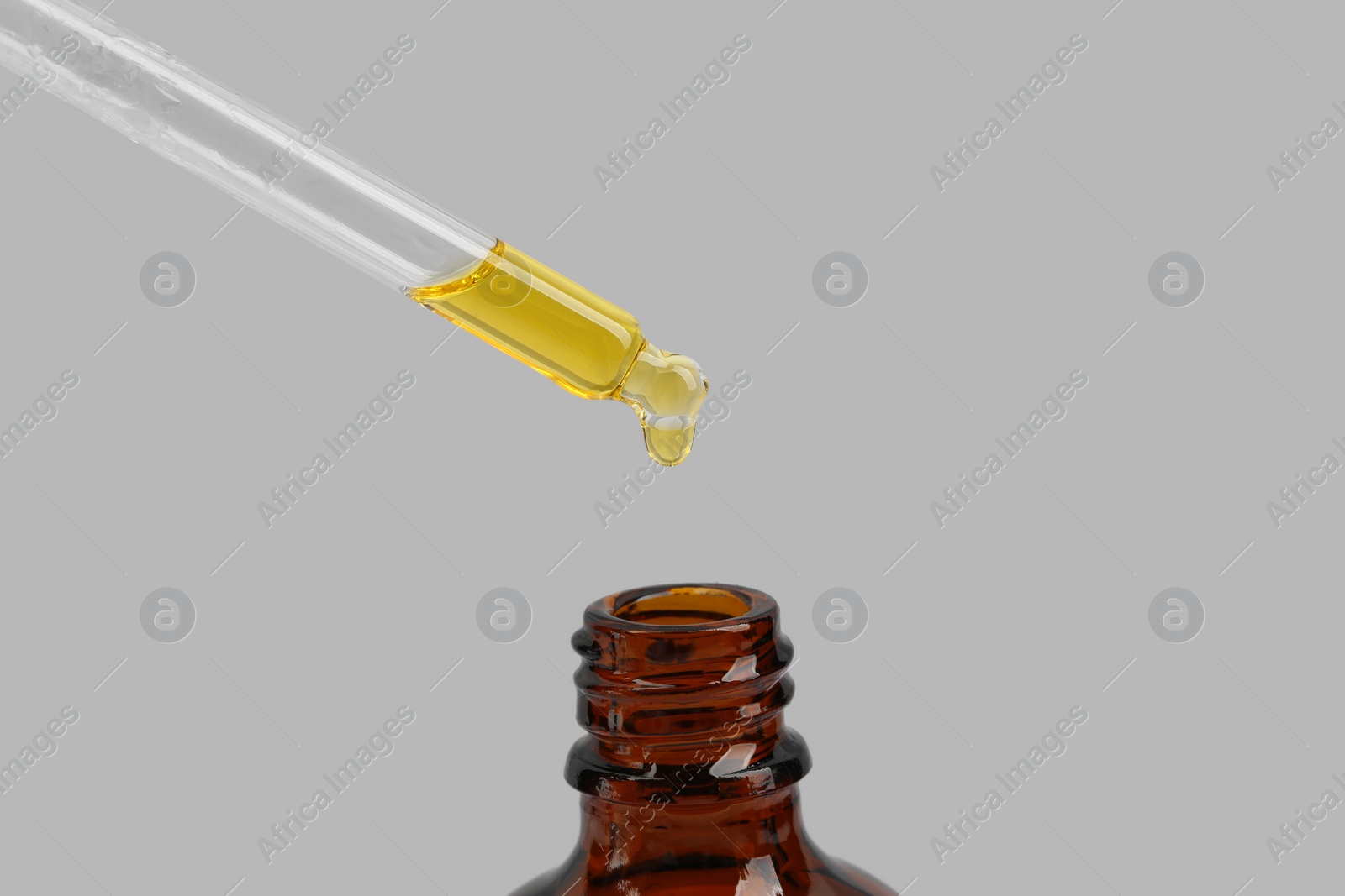 Photo of Dripping tincture from pipette into bottle on white background