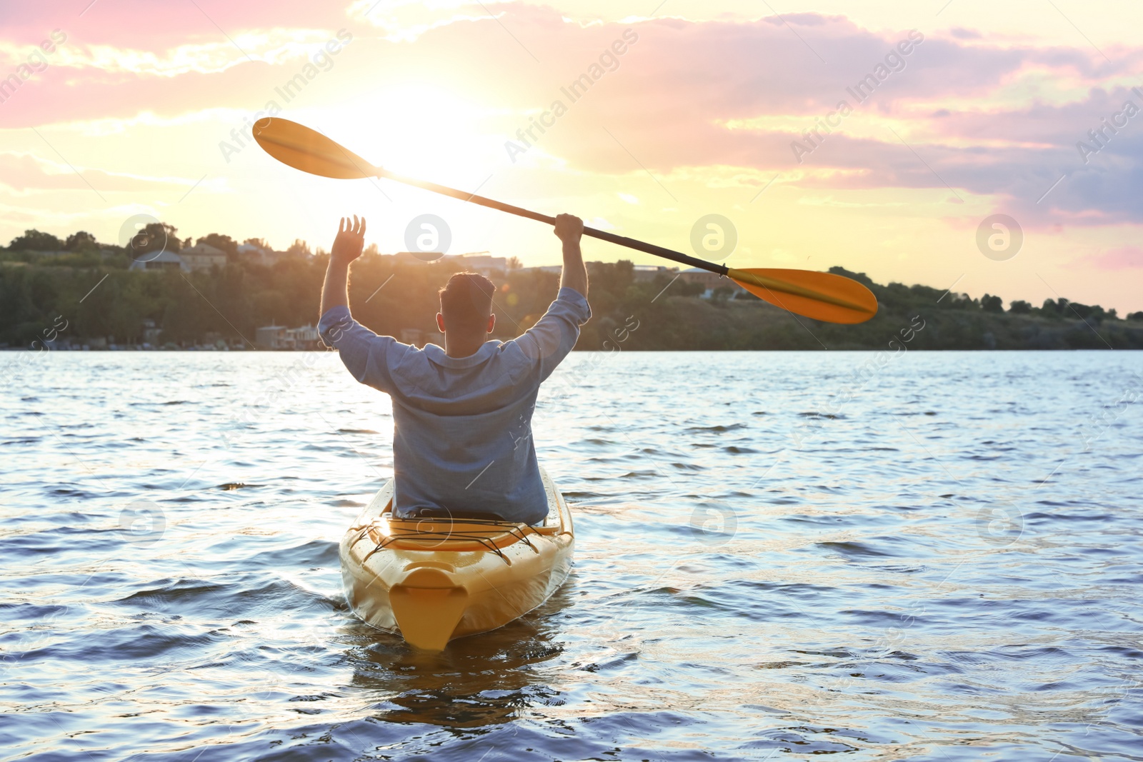 Photo of Man kayaking on river at sunset, back view. Summer activity