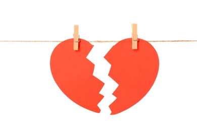 Photo of Halves of paper heart hanging on rope against white background. Relationship problems