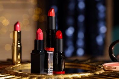 Photo of Beautiful red and pink lipsticks on table against blurred lights