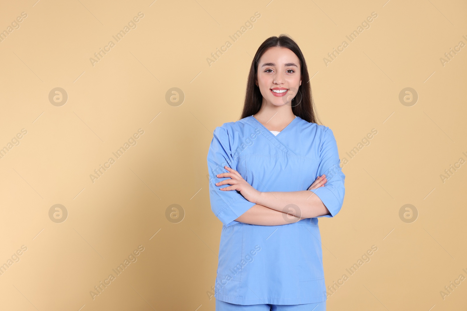 Photo of Portrait of nurse in medical uniform on light brown background, space for text