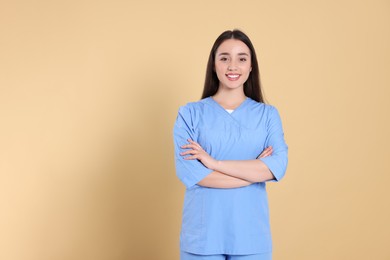 Portrait of nurse in medical uniform on light brown background, space for text