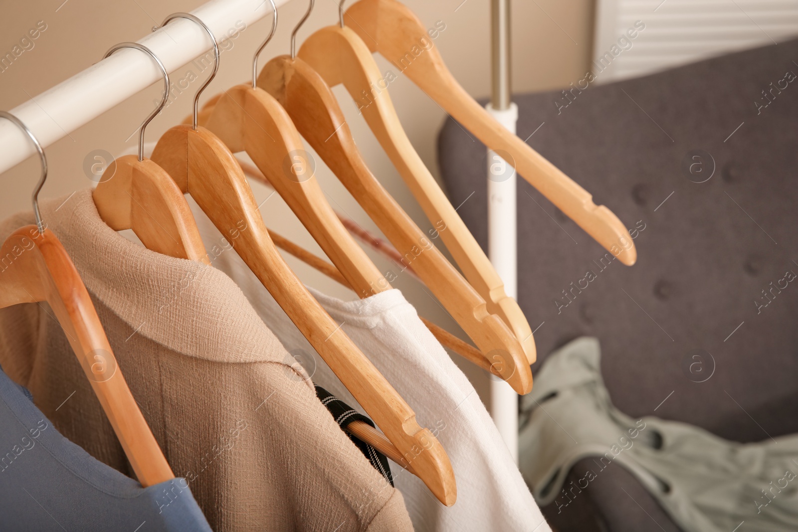 Photo of Hangers with female clothes on wardrobe rack in room, closeup