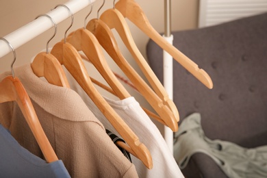 Photo of Hangers with female clothes on wardrobe rack in room, closeup