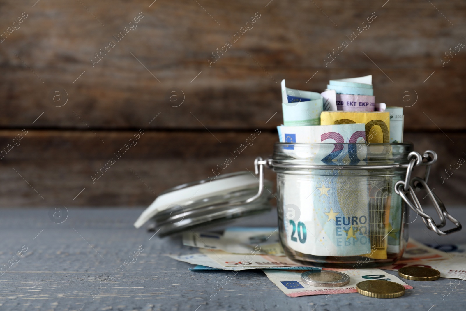 Image of Glass jar full of money on wooden table. Space for text 