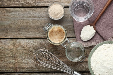 Photo of Leaven, flour, whisk and water on wooden table, space for text