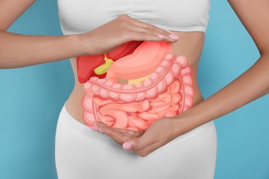 Image of Closeup view of woman with illustration of abdominal organs on her belly against light blue background