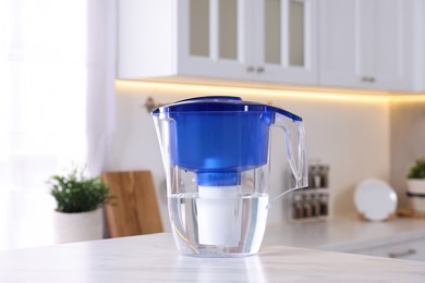 Photo of Water filter jug on white marble table in kitchen, closeup