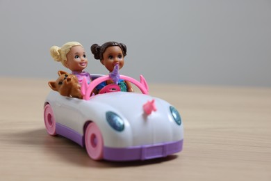 Photo of Leiden, Netherlands - September 20, 2023: Beautiful Chelsea dolls with pet in toy car on wooden table against light gray background, space for text