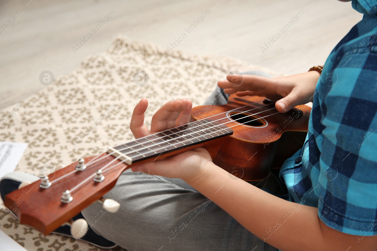 Photo of Little boy playing guitar on floor, closeup