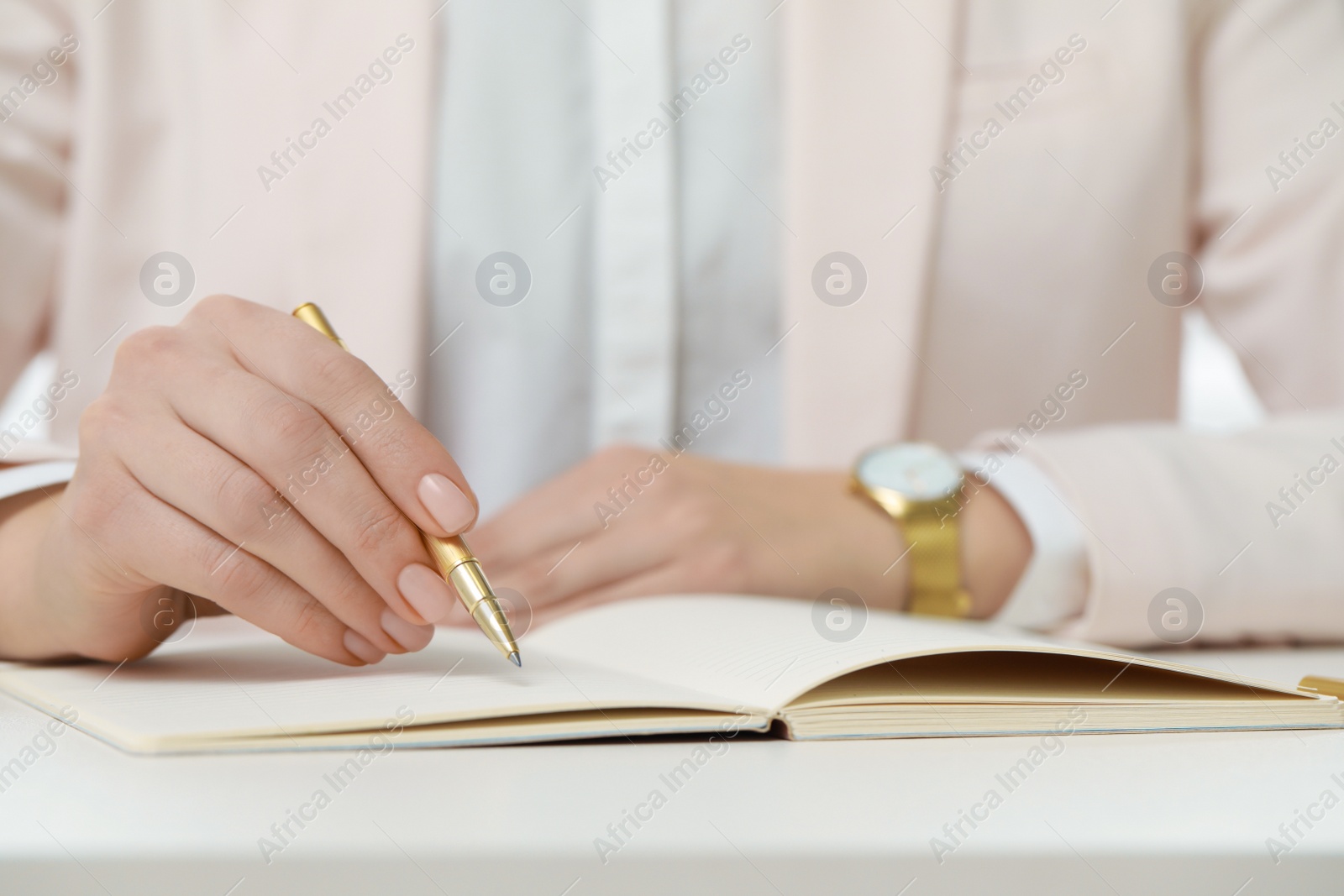 Photo of Woman writing in notebook at white table, closeup