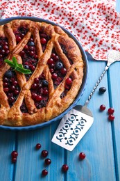 Photo of Delicious currant pie with fresh berries and spatula on blue wooden table