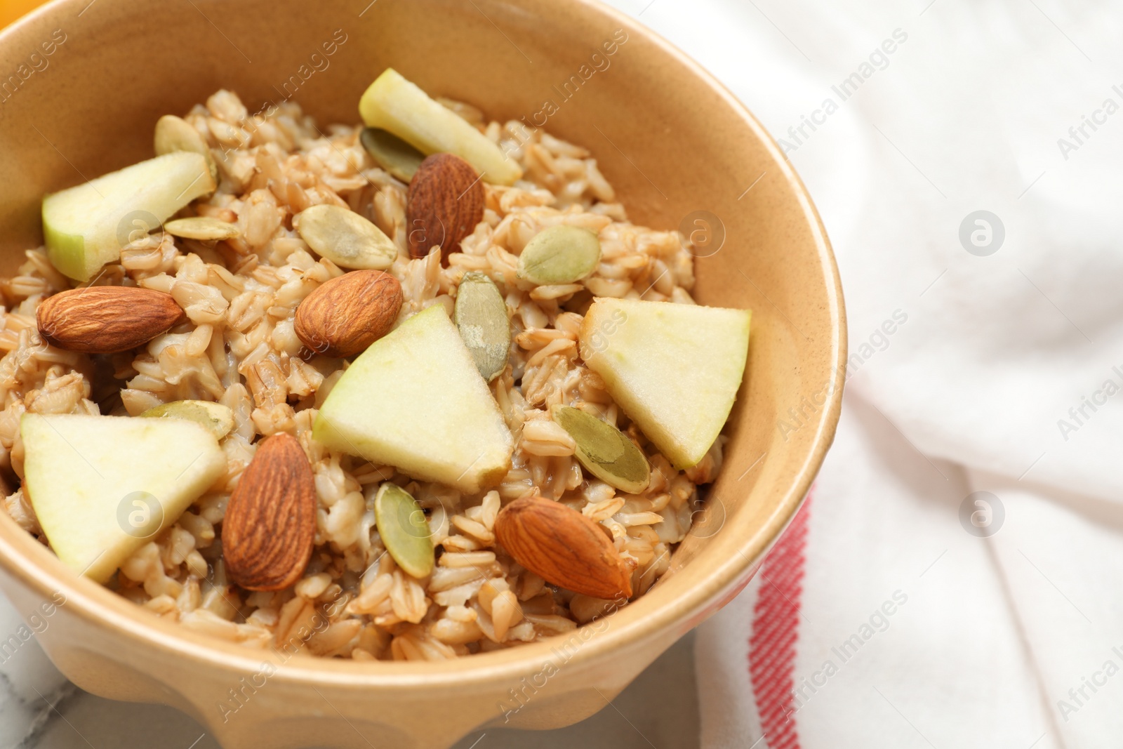 Photo of Tasty oatmeal with apples and almonds on table, closeup. Healthy breakfast