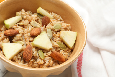 Tasty oatmeal with apples and almonds on table, closeup. Healthy breakfast