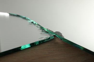 Photo of Shard of broken mirror on wooden backing board, closeup