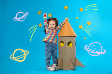 Image of Little child and cardboard rocket near stars on blue background with illustrations