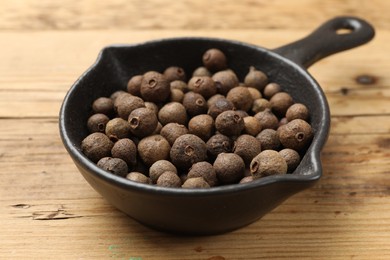 Photo of Dry allspice berries (Jamaica pepper) in dish on wooden table, closeup