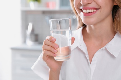 Woman drinking clean water from glass in kitchen, closeup