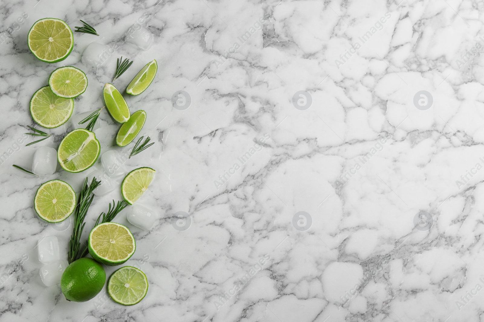 Photo of Lemonade layout with juicy lime slices, rosemary and ice cubes on white marble table, top view. Space for text