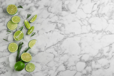 Lemonade layout with juicy lime slices, rosemary and ice cubes on white marble table, top view. Space for text