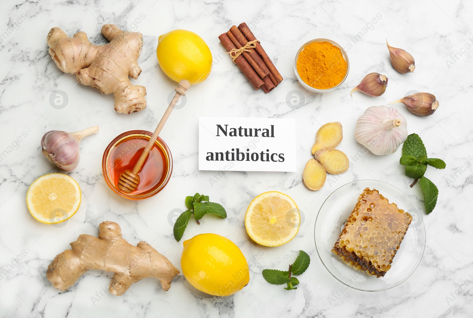 Photo of Different fresh products and card with phrase Natural Antibiotic on white marble table, flat lay