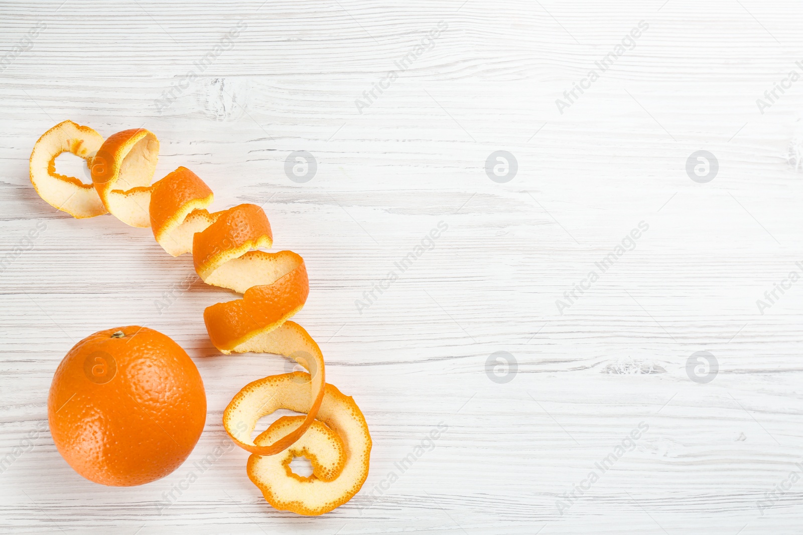 Photo of Orange fruit and peel on white wooden table, flat lay. Space for text